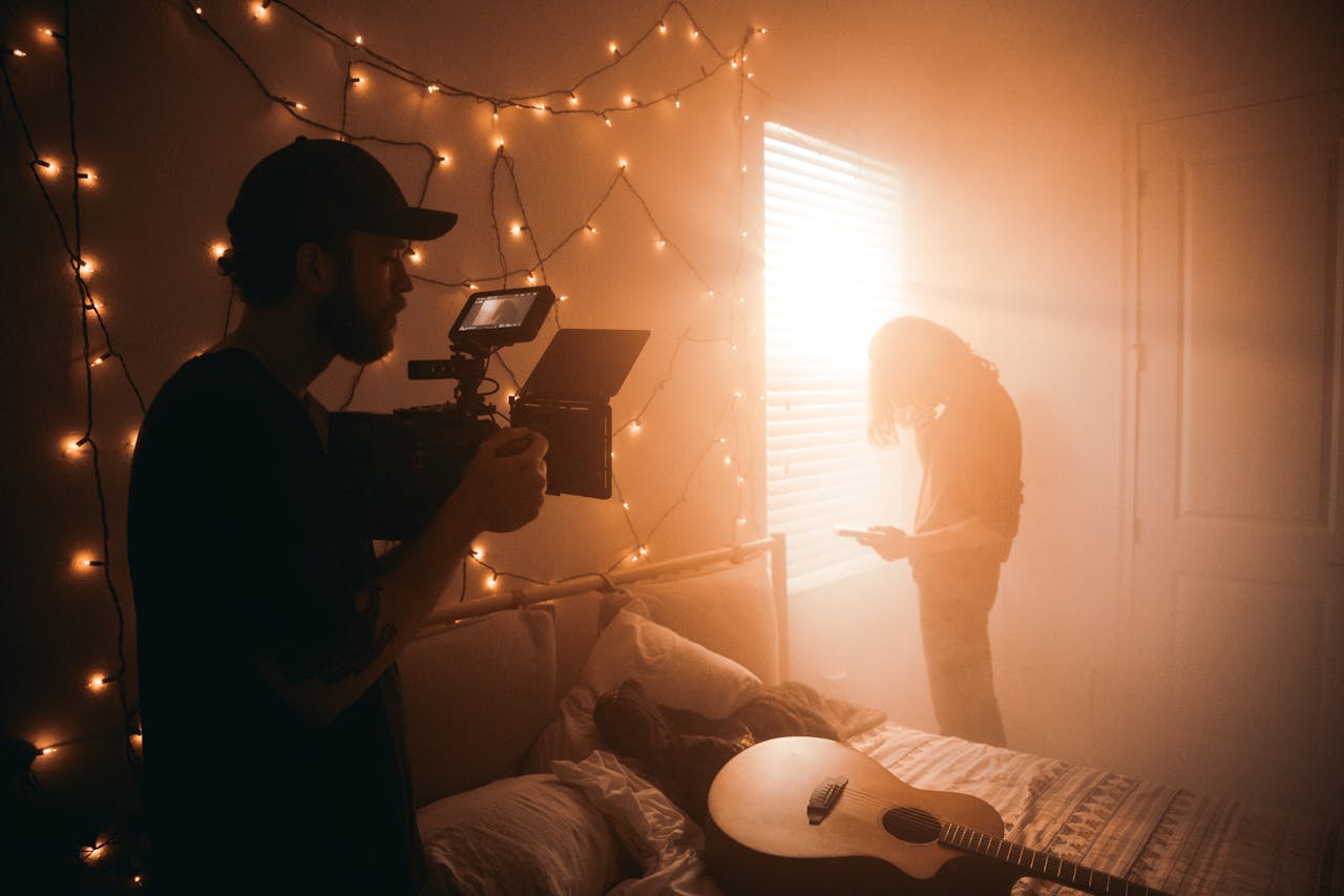 Services A filmmaker captures a scene in a dimly lit bedroom with string lights.